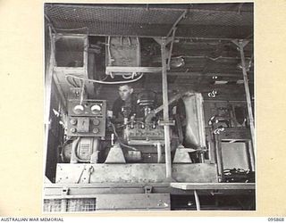 BORAM BEACH, WEWAK AREA, NEW GUINEA. 1945-08-31. CRAFTSMAN G.I. ELDERING, 2/41 LIGHT AID DETACHMENT, CORPS OF AUSTRALIAN ELECTRICAL AND MECHANICAL ENGINEERS, OPERATING A GENERATOR MOUNTED IN A ..