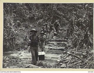 BOUGAINVILLE. 1945-04-18. TROOPS CROSSING THE FORD OVER DAWE CREEK CARRYING HOT STEW FOR C COMPANY, 2/24 INFANTRY BATTALION, WHO ARE CONTINUING THE DRIVE SOUTH TO THE HONGORAI RIVER ALONG THE BUIN ..
