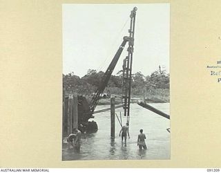 BOUGAINVILLE. 1945-04-23. SAPPERS OF 15 FIELD COMPANY, ROYAL AUSTRALIAN ENGINEERS, WATCHING A MOBILE PILE DRIVER LIFTING A PILE INTO POSITION DURING THE CONSTRUCTION OF A PANEL BRIDGE OVER THE ..