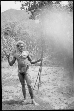Manau, the Chinnery's house boy fitting an arrow into a bow, New Guinea, ca. 1935 / Sarah Chinnery
