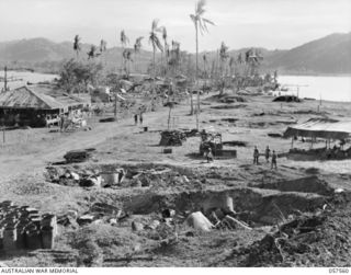 SALAMUA, NEW GUINEA. 1943-09-20. MEMBERS OF THE 162ND AUSTRALIAN LIGHT ANTI-AIRCRAFT BATTERY, AIF., CLEARING THEIR AREA OF WRECKAGE AFTER THE CAPTURE OF THE ISTHMUS. NOTE THE BOMB CRATERS