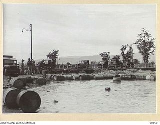 LAE, NEW GUINEA. 1945-10-14. TRAFFIC OF FIRST ARMY ON THE FLOODED ROADWAY WAITING TO CROSS BUTIBUM BRIDGE. FOLLOWING HEAVY RAINS THE BUTIBUM RIVER OVERFLOWED ITS BANKS, FLOODED THE ROAD AND ..