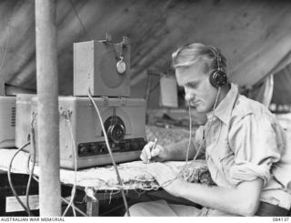 S8759 Telegraphist (Tel) George Robert (Bob) Dunham, Royal Australian Navy Volunteer Reserve, working at an Allied Intelligence Bureau Administrative Post on Wunung Plantation. Tel Dunham was a ..