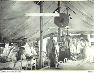 LAE, NEW GUINEA, 1944-07-14. PATIENTS OF THE 2/7TH AUSTRALIAN GENERAL HOSPITAL LISTENING TO A RACE BROADCAST FROM SYDNEY, BEING RELAYED OVER THE HOSPITAL RED CROSS NETWORK