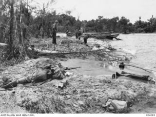 1943-01-14. PAPUA. SMASHED JAPANESE LANDING BARGE AND DEAD JAPANESE LITTER THE BEACH AT BUNA. (NEGATIVE BY BOTTOMLEY)