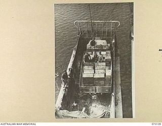 MADANG, NEW GUINEA. 1944-05-12. AN AMERICAN MERCHANT "LIBERTY" SHIP BEING UNLOADED BY DOCKS CONTROL IN THE HARBOUR. THE UNLOADING IS MADE DIRECTLY INTO A 3 TON TRUCK POSITIONED IN A BARGE ALONGSIDE ..