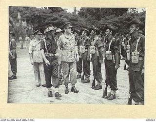 TOROKINA, BOUGAINVILLE. 1945-03-30. LORD WAKEHURST, GOVERNOR OF NEW SOUTH WALES (3), WITH MAJOR W. MCCALL, COMMANDER OF THE GUARD OF HONOUR, 57/60 INFANTRY BATTALION (2), INSPECTING THE FRONT RANK ..