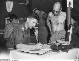 RABAUL, NEW BRITAIN. 1945-11-09. MAJOR G.M. BLAXLAND, MEDICAL OFFICER, 105 CASUALTY CLEARING STATION (1) FILLING IN THE FORM BEFORE DEMOBILISATION MEDICAL EXAMINATION OF CHAPLAIN C.R. JESSOP (2)