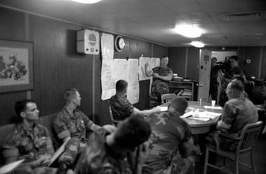 Officers of the 22nd Marine Expeditionary Unit (22nd MEU) gather in the MEU commander's office aboard the amphibious assault ship USS SAIPAN (LHA 2) for a briefing on the situation in and around Monrovia, Liberia. The SAIPAN is on station off the coast of Liberia for Operation Sharp Edge