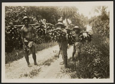 Local people carrying bunches of bananas, Tahiti