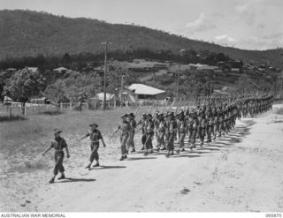 HERBERTON, QLD. 1944-04-25. PERSONNEL OF HEADQUARTERS, 6TH DIVISION MARCHING TO THE WAR MEMORIAL TO TAKE PART IN THE ANZAC DAY CEREMONY. IDENTIFIED PERSONNEL, LEFT TO RIGHT: VX4740 MAJOR K.R. ..