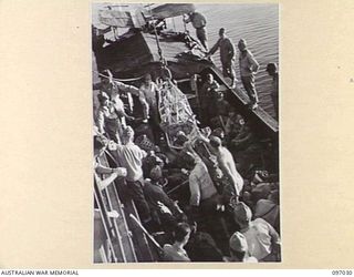 JAPANESE WOUNDED BEING HOISTED FROM A BARGE TO THE DECK OF THE DEBORAH IN A "STOKES LITTER" DURING THEIR EVACUATION FROM NUMA NUMA TO TOROKINA. THE EVACUATION FOLLOWS THE ARRIVAL AT NUMA NUMA ..