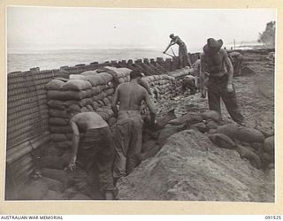 BOUGAINVILLE, 1945-05-02. SAPPERS OF 5 FIELD COMPANY, ROYAL AUSTRALIAN ENGINEERS, CONSTRUCTING A SEA WALL OF SANDBAGS AND SHEET IRON ON THE MOTUPENA POINT - TOKO ROAD. THE DAMAGE CAUSED BY HEAVY ..