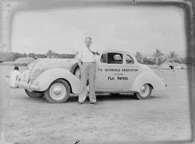 [Man stands beside a Fiji Patrol car]