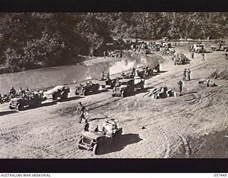 FINSCHHAFEN, NEW GUINEA. 1943-09-22. TRANSPORT OF THE FINSCHHAFEN FORCE ON THE BEACH WAITING TO BE LOADED INTO LANDING SHIP, TANK (LST)