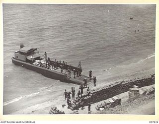 KANGU HILL, BOUGAINVILLE. 1945-10-05. NATIVES UNLOADING STORES FROM AN AUSTRALIAN LANDING CRAFT FOR AUSTRALIAN NEW GUINEA ADMINISTRATIVE UNIT DISTRICT SERVICES. THE RATIONS ARE PART OF SUPPLIES ..