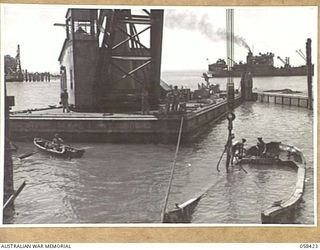 LAE, NEW GUINEA, 1943-10-13. PERSONNEL OF THE UNITED STATES SMALL SHIPS SECTION FASTENING LINES ON TO A SUNKEN JAPANESE BARGE, DURING THEIR HARBOUR CLEARING PROJECT