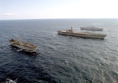 A port view of, from left to right, the amphibious assault ship USS GUAM (LPH-9), the aircraft carrier USS JOHN F. KENNEDY (CV-67) and the British aircraft carrier HMS ARK ROYAL (R-07) underway