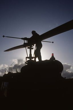 A maintenance crewman inspects a UH-1 Iroquois helicopter of the 19th Air Cavalry, Hawaii Army National Guard, prior to deployment during Exercise OPPORTUNE JOURNEY 85-3