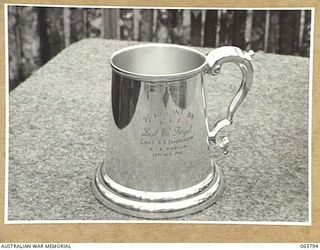 WONDECLA, QLD. 1944-04-15. THE SILVER MEMORIAL MUG DEDICATED TO NX7567 CAPTAIN A.G. SANDERSON OF THE 2/1ST INFANTRY BATTALION WHO WAS KILLED IN ACTION IN PAPUA ON THE 23 OCTOBER 1942. MEMBERS OF ..