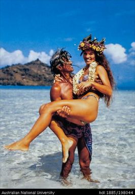French Polynesia - Polynesian man holding woman above beach