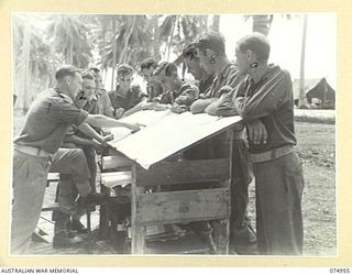 HANSA BAY, NEW GUINEA. 1944-07-29. NX126685 LIEUTENANT J. FOULDS, INTELLIGENCE OFFICER (1) EXPLAINING TO HIS STAFF DETAILS OF MAPS OF THE LOCAL AREAS AT FORWARD BATTALION HEADQUARTERS, 30TH ..