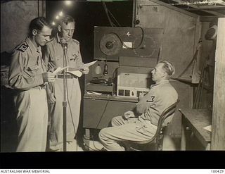 Port Moresby, New Guinea. 1944-05-09. Lieutenant H. M. Sampford, Royal Australian Navy Volunteer Reserve (RANVR) (left), assisting Chaplain F. M. Hill of St John's Church of England (centre) during ..