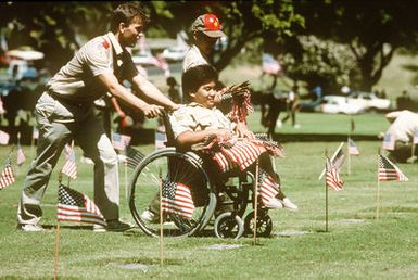 Three Boy Scouts, one in a wheelchair, place American flags on the graves of American veterans in the National Memorial Cemetery of the Pacific in the "Punch Bowl", Honolulu, Hawaii. Exact Date Shot Unknown