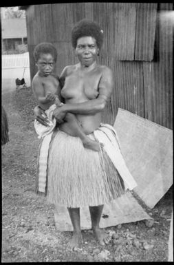 Woman wearing a grass skirt and holding a child, Awar, Sepik River, New Guinea, 1935 / Sarah Chinnery