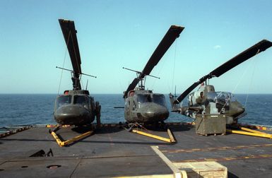 Two UH-1N Iroquois helicopters, right, and an AH-1 Sea Cobra helicopter are parked on the flight deck of the amphibious assault ship USS GUAM (LPH 9) during Exercise SOLID SHIELD '87