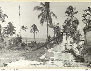 JACQUINOT BAY, NEW BRITAIN. 1944-11-21. 23726 CORPORAL A.R. MCALLISTER, RAAF RELAXES ON THE STEPS OF THE RUINED HOMESTEAD ON THE PALMALMAL PLANTATION