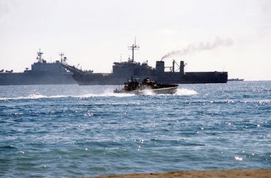 A utility landing craft carrying an M-60 tank approaches the tank landing ship USS BARNSTABLE COUNTY (LST-1197) during Exercise Crisex '81. The amphibious assault ship USS SAIPAN (LHA-2) is also visible in the background