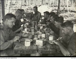 AITAPE, NORTH EAST NEW GUINEA. C. 1944-06. RAAF MEN WORKING ON AN AIRSTRIP HAVE LUNCH AT A TABLE SALVAGED FROM A WRECKED JAPANESE SHIP