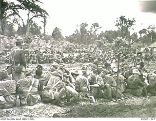THE SOLOMON ISLANDS, 1945-09-19. JAPANESE TROOPS FROM NAURU ISALND AND AUSTRALIAN GUARDS SEATED IN A SECTION OF THE INTERNMENT CAMP ON BOUGAINVILLE ISLAND. (RNZAF OFFICIAL PHOTOGRAPH.)