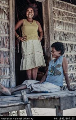 Two relaxed women standing in the doorway sharing a joke