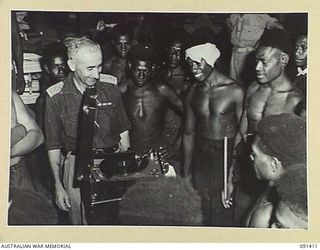 JACQUINOT BAY, NEW BRITAIN, 1945-04-28. CAPTAIN W.E. PARKER, AUSTRALIAN COMFORTS FUND COMMISSIONER (1), PUTS A HOT SWING NUMBER ON THE GRAMAPHONE FOR THE BENEFIT OF THE NATIVE BOYS