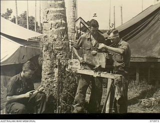 ALEXISHAFEN, NEW GUINEA. 1944-06-10. MEMBERS OF 2/15TH FIELD AMBULANCE WHO ARE FILLING IN SPARE TIME BY MANUFACTURING SOUVENIRS FROM ABANDONED JAPANESE MATERIALS. LEFT TO RIGHT: TX5847 DRIVER A. E. ..