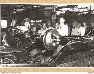 1944-01-26. AUSTRALIAN AND NEW GUINEA ADMINISTRATION UNIT NATIVES WATCHING THE ASSEMBLING OF A MOTOR CAR CHASSIS MOUNTED ON AN ASSEMBLY LINE AT THE FACTORY OF THE FORD MOTOR COMPANY