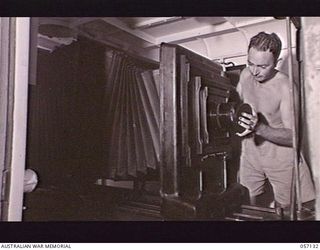 SEVENTEEN MILE, NEW GUINEA. 1943-09-23. NX47245 LANCE CORPORAL E. C. BELL OF THE 2/1ST AUSTRALIAN ARMY TOPOGRAPHICAL SURVEY COMPANY REPLACING THE LENS HOOD AFTER OPERATING THE UNIT'S NEW ..