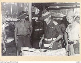 FAURO ISLAND, BOUGAINVILLE AREA. 1945-11-11. LIEUTENANT COLONEL H.L.E. DUNKLEY, COMMANDING OFFICER, 7 INFANTRY BATTALION, AND MEMBERS OF THE INSPECTION PARTY, INSPECTING BREAD BAKED BY JAPANESE ..