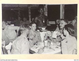 TOROKINA, BOUGAINVILLE. 1945-05-12. PERSONNEL ATTENDING THE OPENING OF THE ARMY OFFICERS CLUB BEING SERVED BY A NATIVE WAITER. IDENTIFIED PERSONNEL ARE:- CAPTAIN O.B. ANDERSON, B CORPS SIGNALS (1); ..