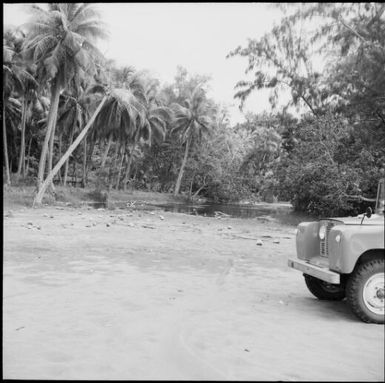 A jeep parked near estuary with palm trees, Vanuatu, 1969 / Michael Terry