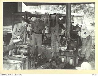 LAE-NADZAB, NEW GUINEA. 1944-07-25. PERSONNEL OF THE 8TH LINES OF COMMUNICATION SALVAGE DEPOT CHECKING AND TESTING CAPTURED JAPANESE BATTERY CHARGERS AND LIGHTING PLANTS AT THEIR HEADQUARTERS. ..