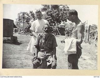 MALAGUNA ROAD, RABAUL, NEW BRITAIN. 1945-09-22. A FORMER INDIAN PRISONER OF WAR WHO POSED A PROBLEM TO 4 FIELD AMBULANCE BARBER, PRIVATE R. THOMPSON. IN THE BACKGROUND STANDS PRIVATE J. TATE