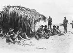 PONGANI, NEW GUINEA. 1942-10. MEMBERS OF 2/6TH AUSTRALIAN INDEPENDENT COMPANY GATHER IN THE SHADE OF A CRUDE NATIVE SHELTER WHILE THEY PARTAKE OF RATIONS. SHOWN ARE: TROOPER (TPR) D. BARDON (1); ..