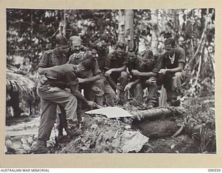 WONGINARA MISSION, NEW GUINEA. 1945-04-07. "I" SECTION, 2/3 INFANTRY BATTALION TROOPS CONFERRING OVER A MAP SPREAD OUT ON A WEAPON PIT. IDENTIFIED PERSONNEL ARE:- LIEUTENANT F.G. BELL (1); PRIVATE ..