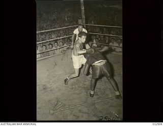 MOROTAI ISLAND, HALMAHERA ISLANDS, NETHERLANDS EAST INDIES. 1945-04-29. WELTERWEIGHT CHAMPION OF NEW GUINEA KEN ALEXANDER OF MELBOURNE, VIC (LEFT), RETURNS TO THE ATTACK IN VIGOROUS ENCOUNTER WITH ..