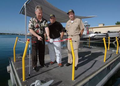 U.S. Navy Officials cut the ribbon on the Navy's latest painting devices, an improved paint float that allow Sailors to paint the freeboard, waterline and boot top safely, during a Ceremony held at Naval Station Pearl Harbor, Hawaii, on Nov. 8, 2006. Pictured left-to-right: Keith Nesmith of Naval Station Pearl Harbor Port Operations; Louis DiStefano, Naval Sea Systems Command Engineering; and CAPT. Taylor Skardon, Naval Station Pearl Harbor Commanding Officer. (U.S. Navy PHOTO by Mass CHIEF Communication SPECIALIST David Rush) (Released)