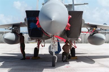 Front view of a US Air Force (USAF) F-15C Eagle aircraft on the flight line at Anderson AFB, Guam as Technical Sergeant (TSGT) Jeffery Reichel (left) and SENIOR AIRMAN (SRA) Jimmy West, USAF, perform a post flight inspection of the aircraft