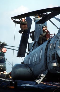 Flight deck crewmen service a Marine Medium Helicopter Squadron 261 (HMM-261) CH-46E Sea Knight helicopter on the amphibious assault ship USS GUAM (LPH-9)